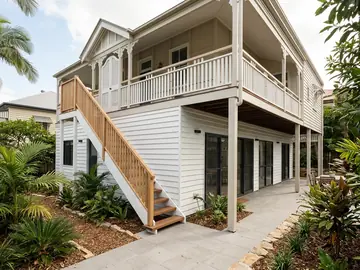 New lower level built under a raised Queenslander, with white weatherboards and timber stairs