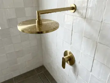 Brushed brass rainfall shower and wall mixer in a tiled walk-in shower